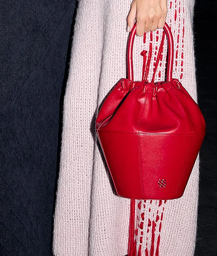 Imagen secundaria 2 - De arriba abajo, imagen del backstage del desfile de otoño-invierno 2026/2027 de Simorra; detalle del bolso Tinaja; y look con palabras escritas de la colección Texere.