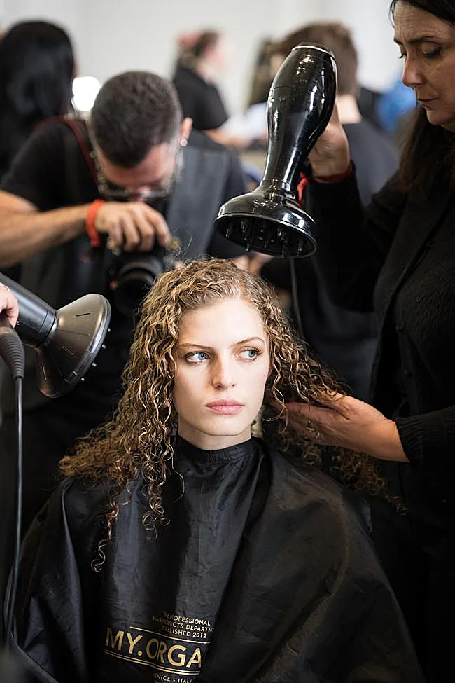 Un estilista secando el cabello de una modelo.